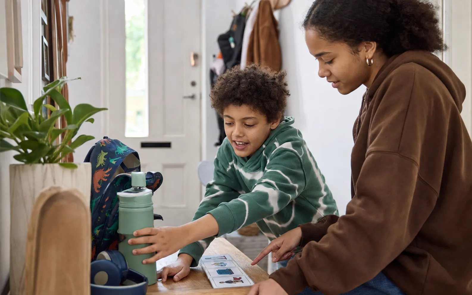 A child and teenage sibling preparing a bag using a picture-based sequence card